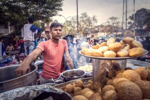 Disgruntled street food vendor with unhappy expression facing a traveler in a crowded market