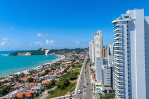 Aerial view of Natal, Brazil, showcasing city high rises and the iconic Careca Dune in the distance.